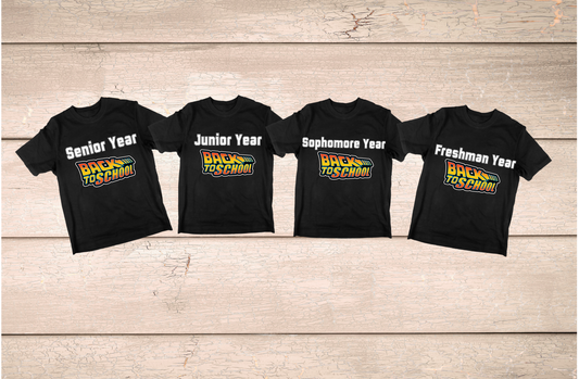 Four black t-shirts with different year labels on a wooden surface